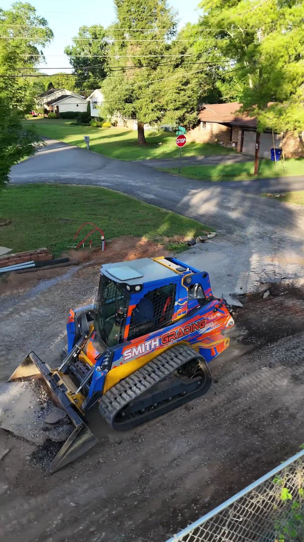 Construction site with a blue and orange bulldozer from Smith Grading on gravel road.
