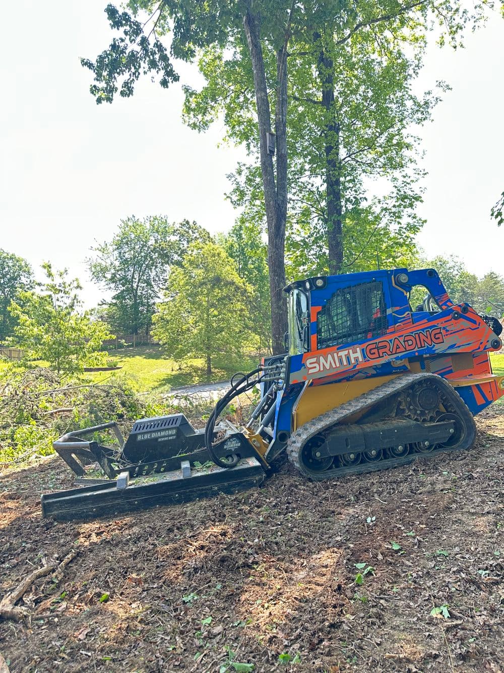 Smith Grading machinery clearing land, showcasing tracked equipment in a wooded area.